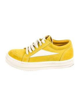 A yellow suede sneaker with white laces and a white side logo, featuring a thick sole and a sleek, casual design.