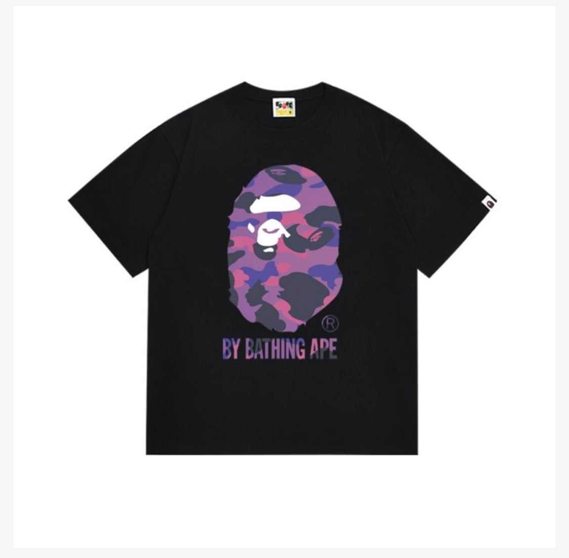 A black t-shirt featuring a purple and pink camouflage BAPE ape face design with the text "BY BATHING APE" underneath.