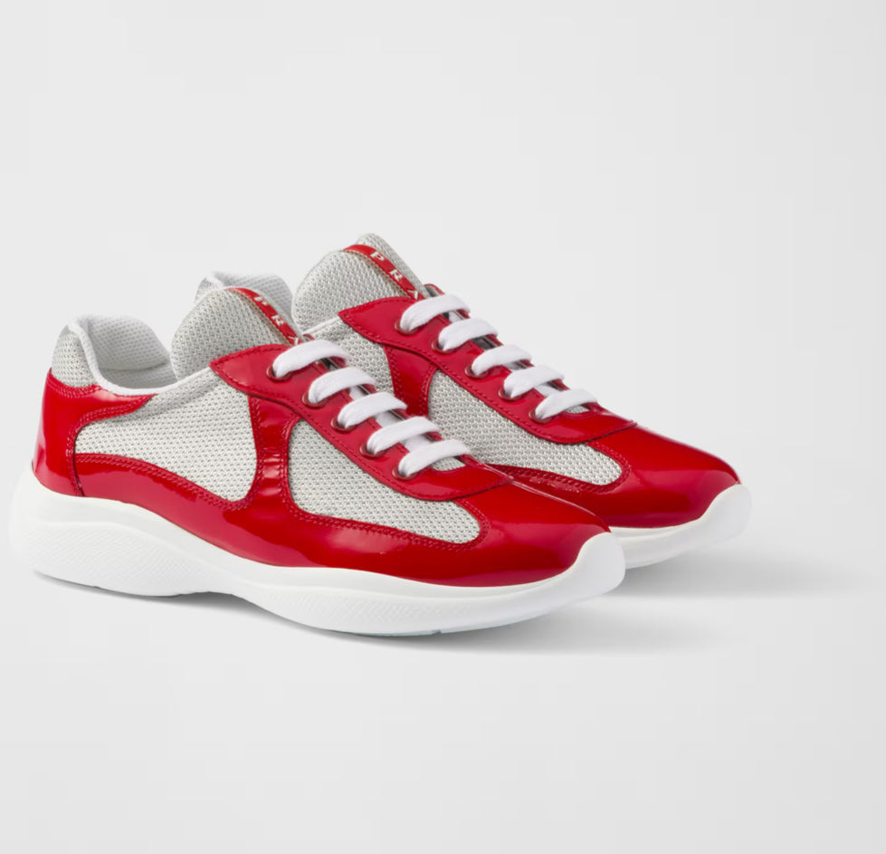 Red and white sneakers with mesh panels, glossy red accents, and white laces, displayed from the side.