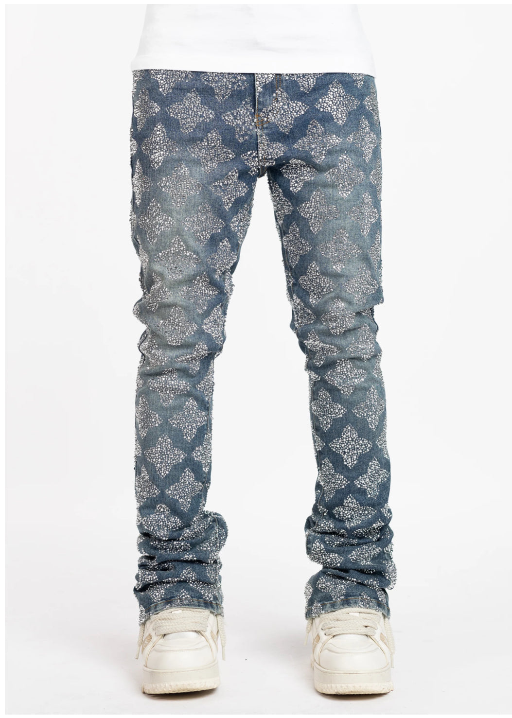 A close-up of blue jeans with a patterned design of silver flowers, paired with white sneakers, and a plain white shirt above.