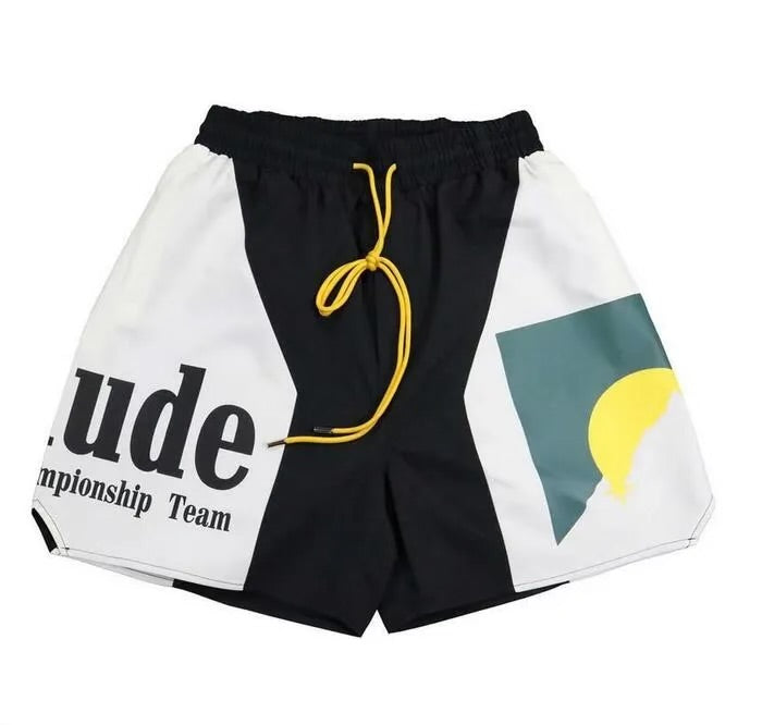 Pair of black and white shorts with bold text "attitude championship team" and yellow drawstring on a white background.