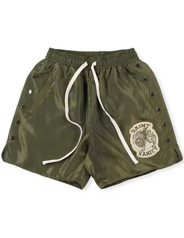 Olive green shorts with white drawstrings, side snap buttons, and a Saint Vanity logo on the left leg.