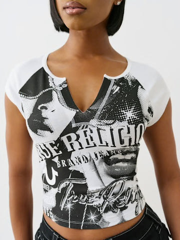 Woman wearing a fitted black and white graphic True Religion top with a V-notch neckline, styled with black jeans against a plain background.