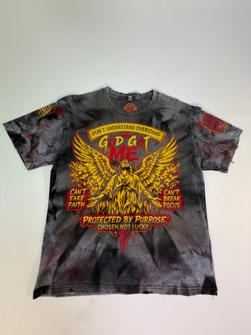 A short-sleeve graphic t-shirt with a distressed black and gray acid-wash finish, featuring a large red and yellow graphic of a winged figure and text including 'GOD GOT ME' and 'PROTECTED BY PURPOSE'.