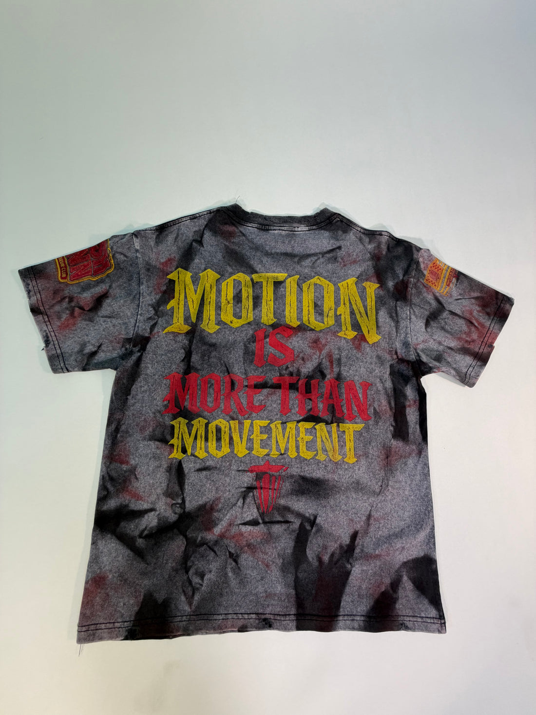 A short-sleeve graphic t-shirt with a distressed black and gray acid-wash finish, featuring a large red and yellow graphic of a winged figure and text including 'GOD GOT ME' and 'PROTECTED BY PURPOSE'.