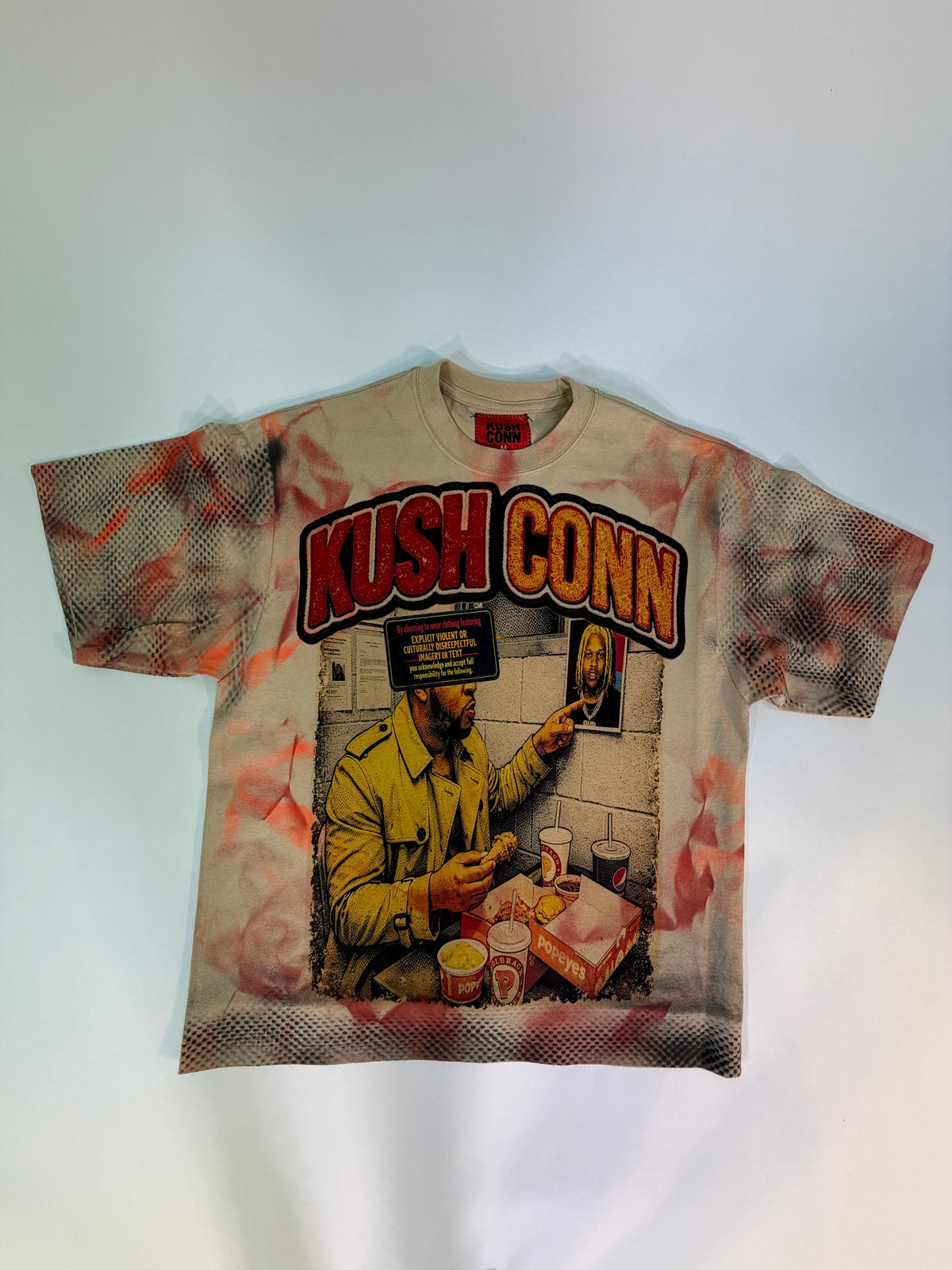 A vintage-style graphic t-shirt featuring a large 'KUSH CONN' print with a illustrated figure in a yellow jacket, laid flat against a light background.