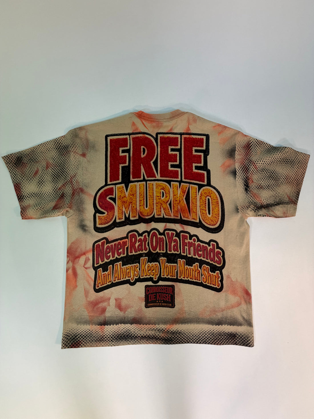 A vintage-style graphic t-shirt featuring a large 'KUSH CONN' print with a illustrated figure in a yellow jacket, laid flat against a light background.